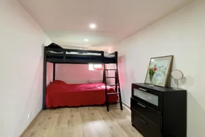 Chambre avec lits superposés dans l’appartement du château de Villers-sur-Mer, parquet clair, murs blancs et décoration sobre, idéale pour un espace nuit fonctionnel dans le Calvados.