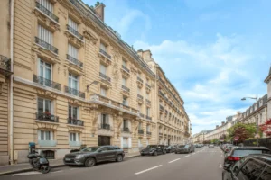 Façade d’un immeuble haussmannien en pierre de taille situé rue de la Pompe à Paris 16, avec balcons en fer forgé et perspective sur la rue.
