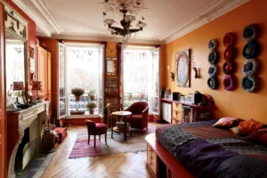 Séjour lumineux avec double ouverture sur balcon, parquet en point de Hongrie, moulures, cheminée et décoration chaleureuse d’un appartement situé rue du Faubourg Saint-Denis à Paris 10.