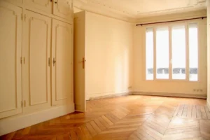 Chambre lumineuse avec parquet point de Hongrie, rangements intégrés et grande fenêtre donnant sur la rue Beaurepaire à Paris 10.