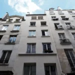 Façade d’un immeuble parisien rue Poissonnière Paris 2, vue depuis la rue, avec fenêtres, garde-corps et ciel dégagé.