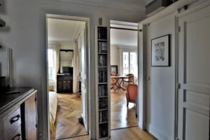 Dégagement lumineux desservant la chambre et le séjour, parquet ancien en point de Hongrie, vue traversante de l’appartement situé rue du Faubourg Saint-Denis Paris 10.