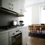 Cuisine ouverte d’un appartement situé rue du Faubourg Saint-Denis à Paris 10, avec plan de travail moderne, électroménager et vue sur la salle à manger.