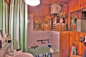 Salle de bain d’un duplex rue du Faubourg Saint-Denis, avec baignoire ancienne, carrelage mural clair, rangements en bois et éléments décoratifs rétro.