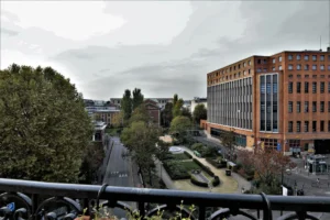 Vue dégagée depuis le balcon de l’appartement donnant sur un square arboré et les immeubles en briques du quartier Faubourg Saint-Denis à Paris 10ᵉ.