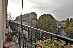 Balcon filant sur cour et rue avec vue sur les immeubles haussmanniens et la végétation du quartier Faubourg Saint-Denis à Paris 10ᵉ.