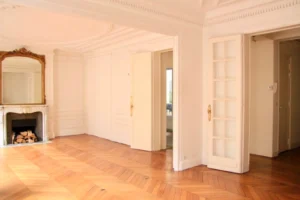 Salon haussmannien lumineux avec parquet point de Hongrie, cheminée en marbre, grand miroir ancien et moulures au plafond, dans un appartement situé rue Beaurepaire à Paris 10.