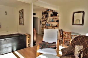 Séjour lumineux avec coin nuit ouvert, fauteuils confortables, grande bibliothèque et table ronde dans un appartement rue Poissonnière Paris 2.