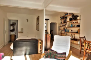 Chambre ouverte sur le séjour avec coffre ancien, rangements intégrés et grande bibliothèque dans un appartement rue Poissonnière Paris 2.