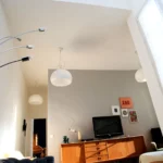 Séjour lumineux d’un appartement rue du Faubourg Saint-Denis à Paris 10, avec verrière haute, buffet vintage en bois, canapé en cuir et décoration contemporaine.