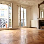 Salon haussmannien lumineux avec parquet point de Hongrie, cheminée en marbre et grandes fenêtres ouvrant sur le balcon, rue Beaurepaire à Paris 10.