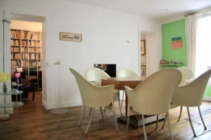 Séjour lumineux d’un duplex du Passage Delanos à Paris 10, avec salle à manger, parquet ancien et bibliothèque attenante.