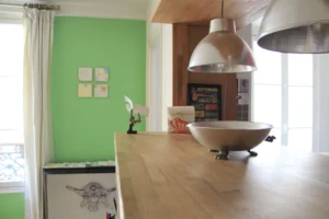 spensions métalliques et mur vert pastel.