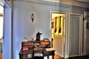 Petit espace bureau avec meuble en bois ancien, éclairage mural et vue sur la cuisine dans un appartement en duplex situé rue du Faubourg Saint-Denis à Paris 10.