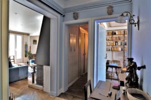 Espace de circulation d’un duplex rue du Faubourg Saint-Denis, avec vue sur le séjour, couloir menant aux rangements et accès à la bibliothèque dans un appartement ancien à Paris 10.