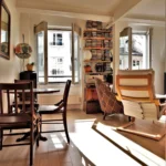 Salon lumineux avec coin repas, fauteuils et fenêtres ouvertes donnant sur cour dans un appartement rue Poissonnière Paris 2.