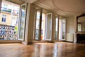 Salon haussmannien avec parquet point de Hongrie et grandes fenêtres ouvrant sur le balcon filant donnant sur la rue Beaurepaire à Paris 10.