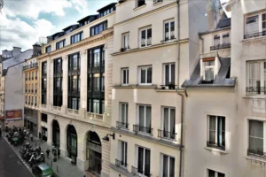 Vue dégagée sur les façades parisiennes de la rue Poissonnière Paris 2, depuis l’appartement, avec immeubles haussmanniens et circulation piétonne.
