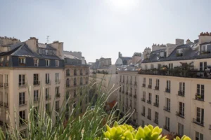 Vue dégagée sur les toits parisiens depuis un appartement duplex rue d’Aboukir, avec immeubles haussmanniens et lumière de fin de journée.