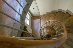 Escalier ancien en colimaçon d’un immeuble rue d’Aboukir, avec marches en bois, rampe courbe et tomettes hexagonales en rez-de-chaussée.