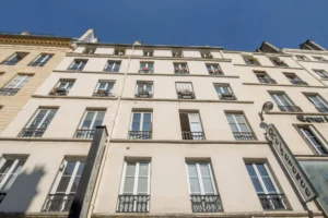 Façade d’un immeuble parisien rue d’Aboukir, au cœur du quartier Sentier–Montorgueil, avec fenêtres alignées et ciel bleu dégagé.
