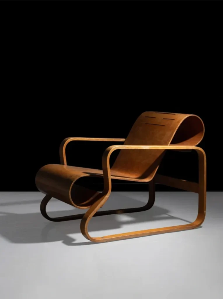 Fauteuil Paimio imaginé par Aino Aalto en 1932 pour un sanatorium en Finlande, en contreplaqué de bouleau courbé, icône du design scandinave alliant forme organique et fonction thérapeutique.