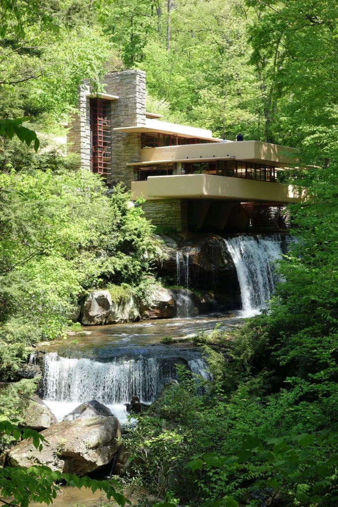 Vue iconique de la maison Fallingwater de Frank Lloyd Wright, construite en 1939 au-dessus d’une cascade au cœur de la forêt de Pennsylvanie, illustrant l’architecture organique parfaitement intégrée à la nature.