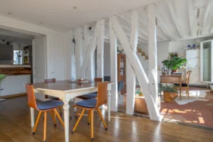 Espace de vie ouvert d’un duplex rue d’Aboukir, avec salle à manger, poutres apparentes blanches, coin bureau, tomettes et parquet, dans une ambiance lumineuse et chaleureuse.