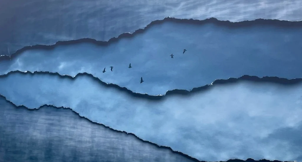 Photographie de Marilia Destot — oiseaux en vol au-dessus de strates bleutées rappelant la mer et l’horizon, œuvre présentée au festival Planches Contact Deauville