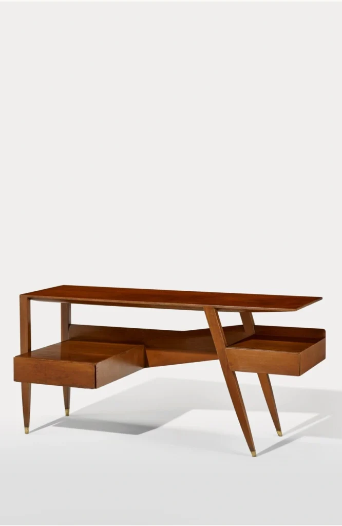 Bureau en bois conçu en 1955 par Gio Ponti pour la Villa Goldschmidt à Caracas, aux lignes asymétriques et effilées, reposant sur des pieds fuselés et intégrant des modules de rangement suspendus.