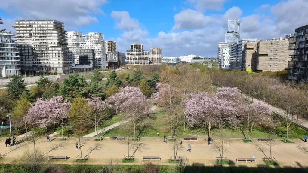 Parc Martin Luther King à Paris 17ᵉ — allées piétonnes, arbres en fleurs et espaces verts au cœur du quartier Clichy-Batignolles, avec les immeubles contemporains en arrière-plan.
