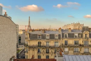 Vue depuis la pièce principale d’un appartement à Paris 15, donnant sur cour avec perspective dégagée sur les toits haussmanniens et la Tour Eiffel au loin.