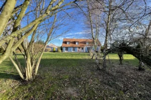 Façade principale d’une maison à vendre à Saint-Benoît-d’Hébertot (14130), avec jardin arboré, garage double et architecture traditionnelle normande.