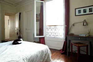 Chambre d’un appartement à Paris 5, quartier des Gobelins, avec parquet ancien, coin bureau près de la fenêtre et belle luminosité naturelle.