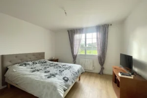 Chambre confortable avec parquet, lit double et fenêtre sur jardin, maison à vendre à Saint-Benoît-d’Hébertot.