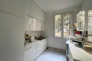 Ancienne cuisine d’un appartement à vendre à Paris 11, boulevard du Temple, pièce à réaménager en salle de bains, avec fenêtre et carrelage mural.