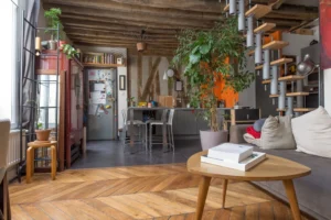 Séjour chaleureux avec parquet en point de Hongrie, cuisine ouverte, escalier design et poutres apparentes dans un appartement de caractère à Paris 10.