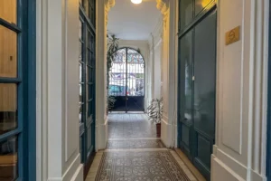 Hall d’entrée d’un immeuble ancien rue Dulong à Paris 17 Pont Cardinet, avec carrelage d’époque, boiseries et porte vitrée sur rue.