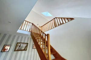 Vue en contre-plongée de l’escalier bois et mezzanine avec puits de lumière, maison à vendre à Saint-Benoît-d’Hébertot.