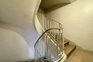 Escalier de la copropriété d’un immeuble de 1965 à Paris 12 Bel Air, parties communes bien entretenues avec rampe courbe et cage d’escalier lumineuse.