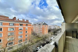 Vue depuis le balcon d’un appartement à vendre à Paris 12 Picpus, perspective dégagée sur les immeubles en brique, rue arborée et environnement résidentiel calme.