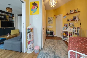 Vue d’ensemble d’une chambre d’enfant d’un appartement à vendre à Paris 18 Place de Clichy, avec rangements intégrés, placards coulissants, parquet ancien, espace jeux et circulation fluide vers le séjour.