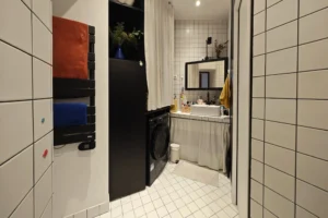 Salle d’eau contemporaine d’un appartement à vendre à Paris 18 Place de Clichy, avec douche, vasque, miroir, carrelage blanc, rangements intégrés et espace buanderie discret.