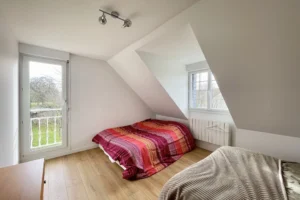 Chambre sous combles avec accès balcon, lumière naturelle et espace nuit cosy, maison à vendre à Saint-Benoît-d’Hébertot.