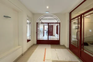 Hall d’entrée d’un immeuble parisien avec portes vitrées et parties communes soignées, immeuble de l’appartement à vendre à Paris 11, boulevard du Temple.
