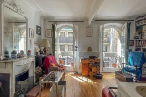 Salon d’un appartement à Paris 17 Pont Cardinet, parquet ancien, cheminée décorative, moulures au plafond et grandes fenêtres apportant une belle lumière naturelle.