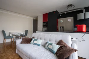 Vue du séjour avec canapé et coin repas, cuisine ouverte équipée avec électroménager intégré, appartement 2 pièces lumineux à Paris 12 secteur Dugommier Daumesnil.