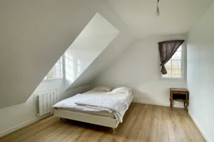 Chambre avec plafond mansardé, parquet clair et mobilier sobre, maison à vendre à Saint-Benoît-d’Hébertot.
