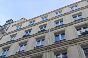 Façade d’un immeuble ancien à Paris 18 Place de Clichy, architecture haussmannienne, fenêtres à garde-corps en ferronnerie et environnement urbain recherché.