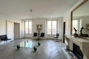 Séjour d’un appartement à vendre à Paris 11, boulevard du Temple, avec parquet en point de Hongrie, cheminée en pierre, grandes fenêtres et belle luminosité naturelle.